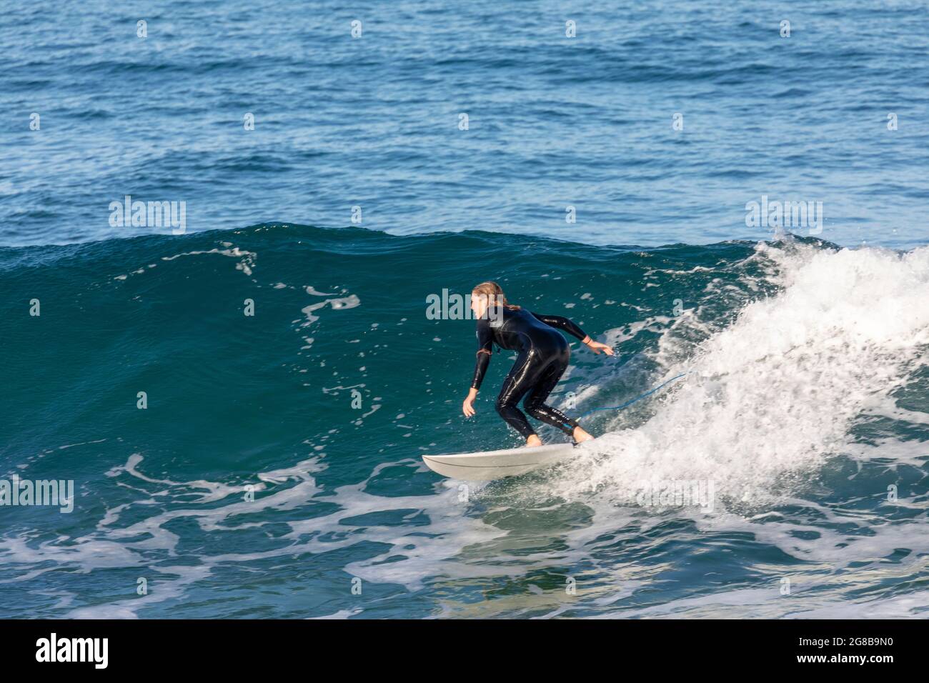 Australian teenage woman girl in wetsuit surfing the waves on his