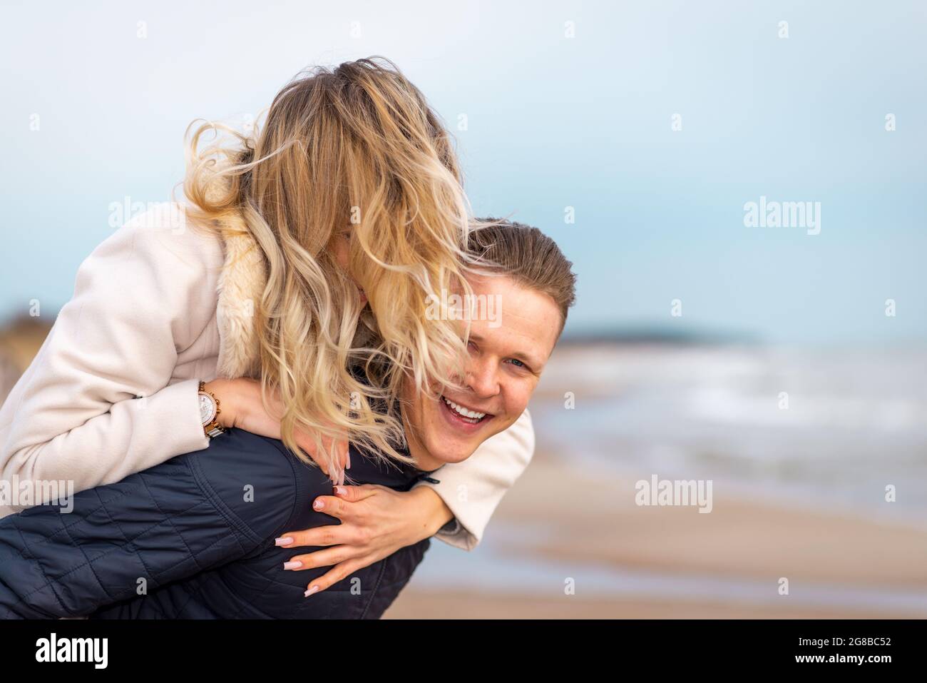 Man giving and adult woman a piggyback ride laughing and having fun in San  Diego, California. Stock Photo