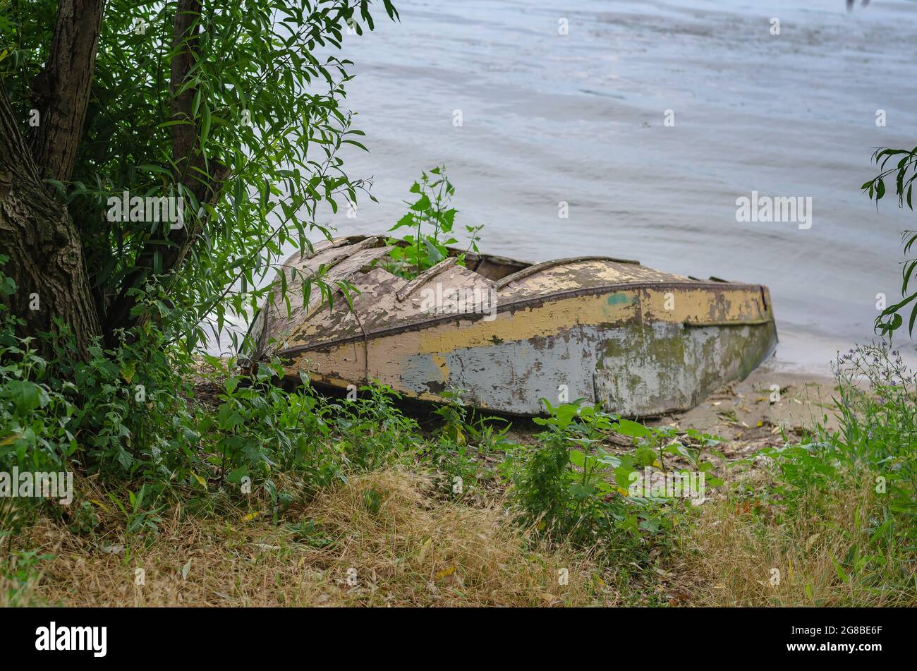 An old ruined wooden boat on the shore. A small fishing boat lies ...