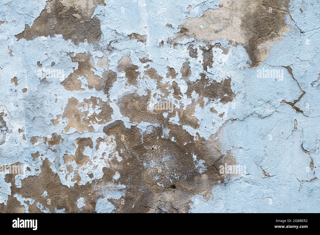 Old concrete wall with peeling paint. Close-up of blue ruined cement wall. Abstract grunge stucco texture. Cracked surface of plaster Stock Photo