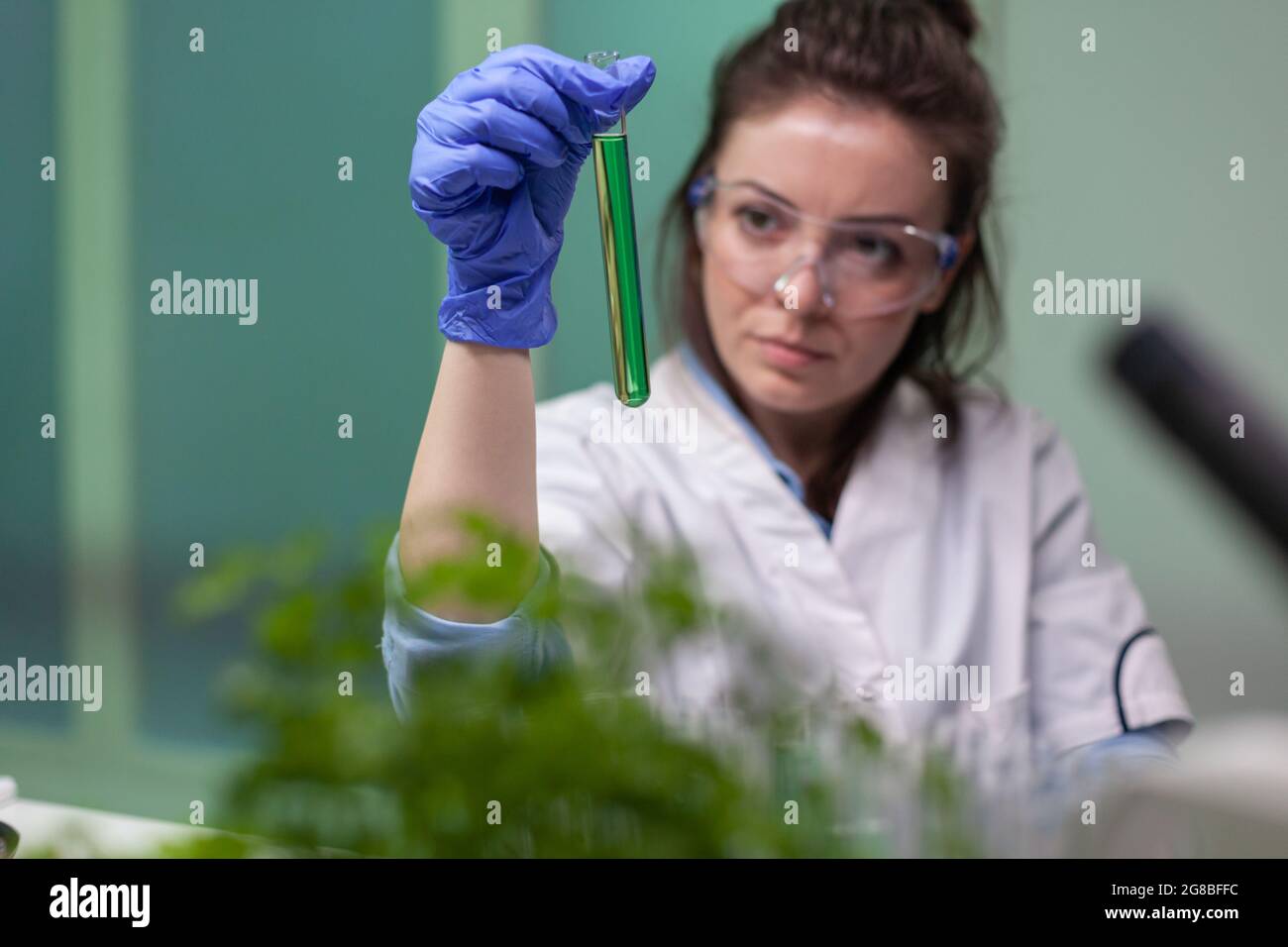 Chemist researcher woman holding test tube with dna liquid observing