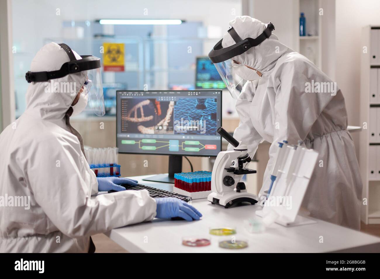 Scientists in protection suits analysing dna sample infected with virus. Team doctors working with various bacteria, tissue and blood samples, pharmaceutical research for antibiotics Stock Photo