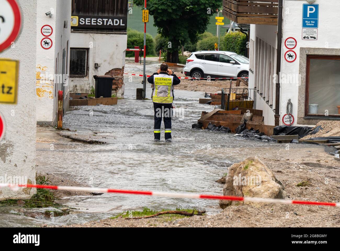 19 July 2021, Bavaria, Königssee: A firefighter stands on a road leading to the Königssee lake, over which water is still flowing away. More than 160 people had to be brought out of their homes to safety in the holiday region around Königssee after the weekend's storm. Photo: Peter Kneffel/dpa Stock Photo