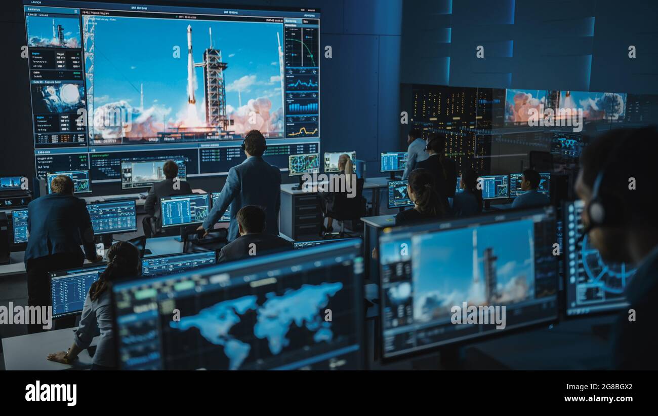 Group of People in Mission Control Center Witness Successful Space Rocket Launch. Flight Control Employees Sit in Front Computer Displays and Monitor Stock Photo