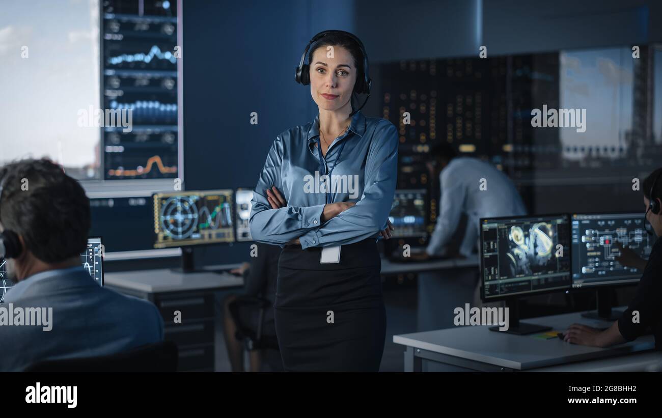 Portrait of a Beautiful Female Flight Controller Posing for Camera in a Mission Control Center. Successful Woman Wearing a Headset and Crossing Her Stock Photo