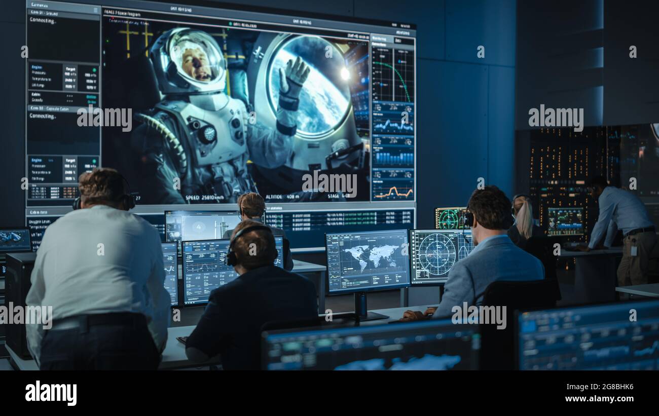 Group of People in Mission Control Center Establish Successful Video Connection on a Big Screen with an Astronaut on Board of a Space Station. Flight Stock Photo