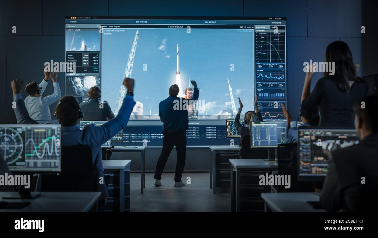 Group of People in Mission Control Center Witness Space Rocket Launch. Flight Director is Pacing Nervously in Front of the Screen. Stock Photo