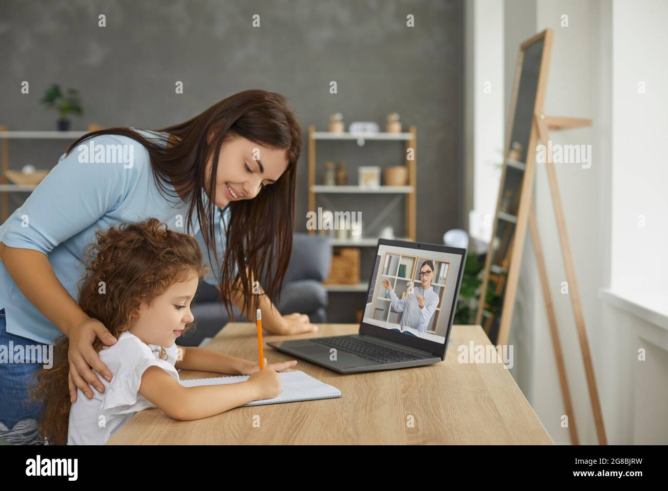 Happy mother and child having online class with school teacher on laptop computer Stock Photo