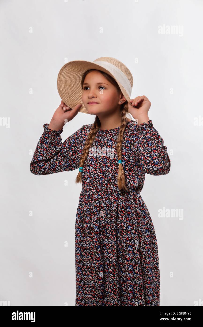 Portrait of young funny girl holding your sun hat tightly,  isolated on white. Stock Photo