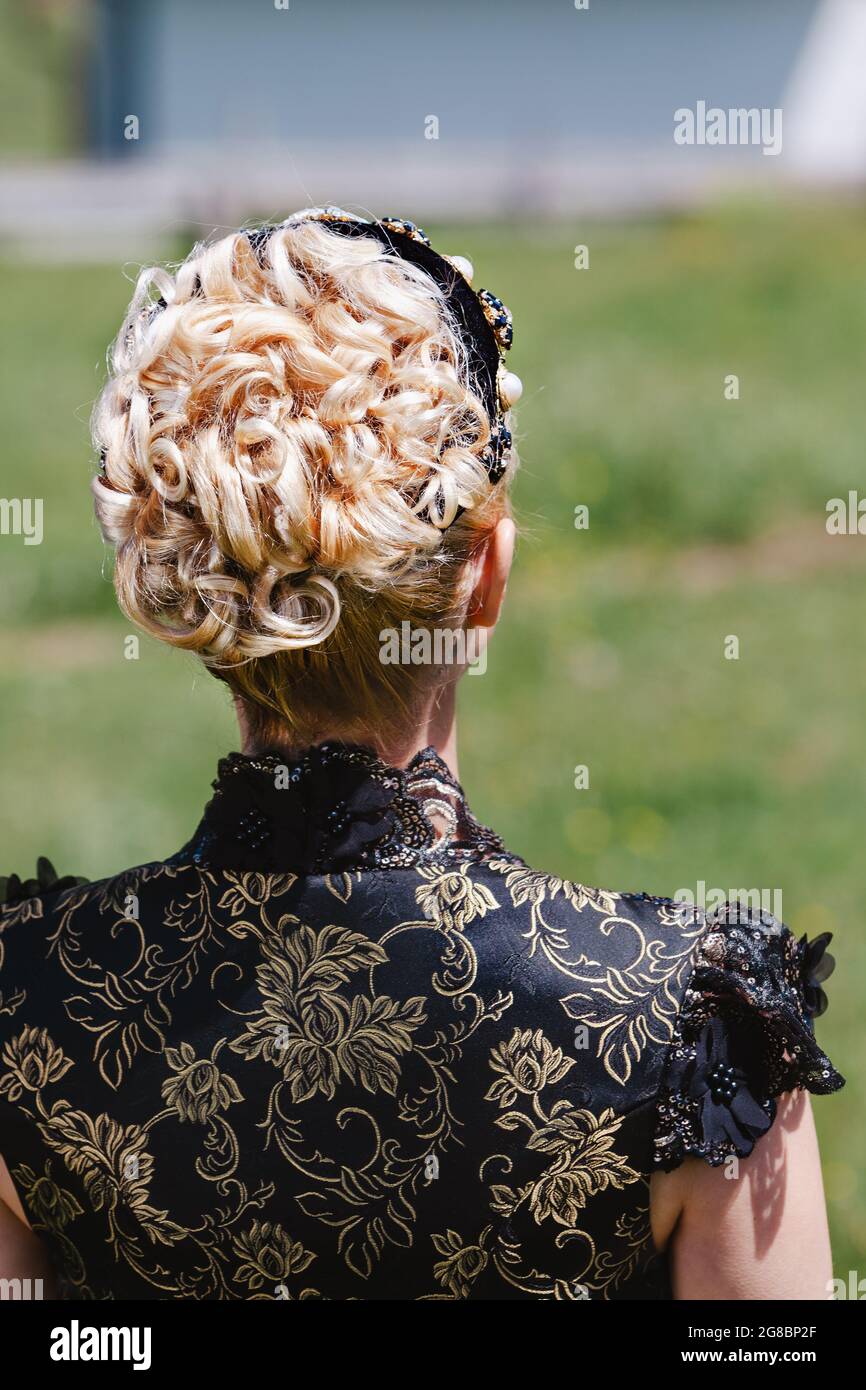 Portrait of blonde woman in lace dress with headband and curly hair , from behind Stock Photo