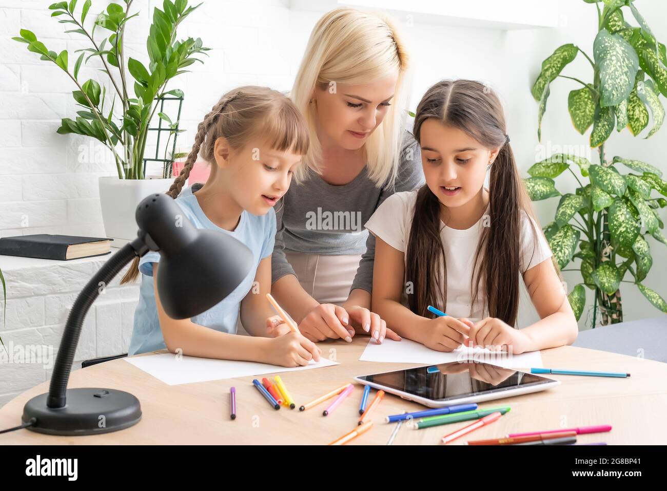 Beautiful young mother helping her daughters with homework Stock Photo ...