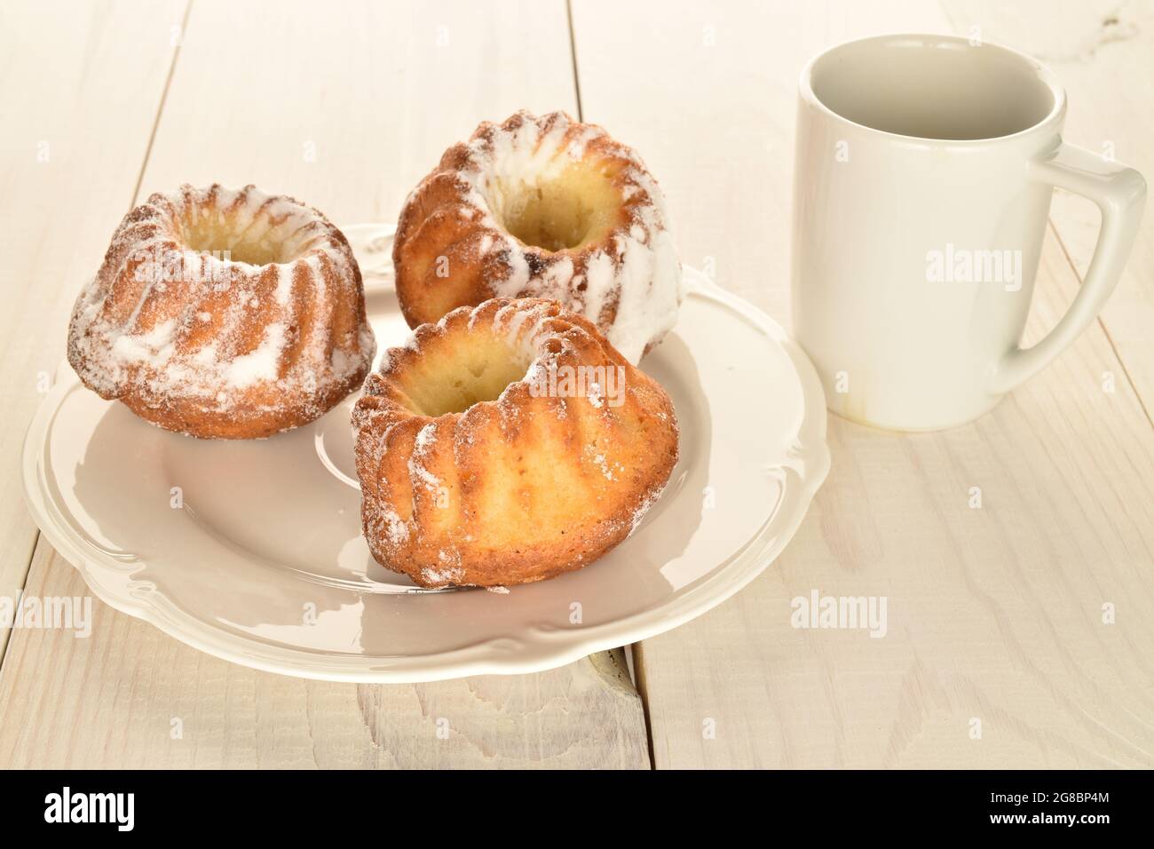 Three homemade sweet cupcakes on a ceramic plate with a white cup ...