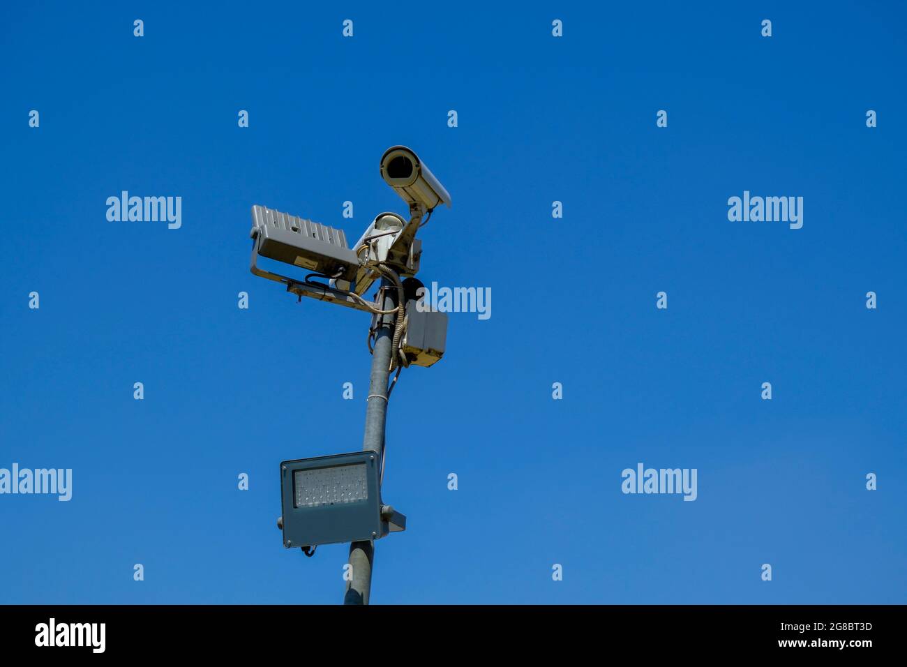 cctv security camera close-up with a lamp on sun battery across blue sky . Security system Stock Photo