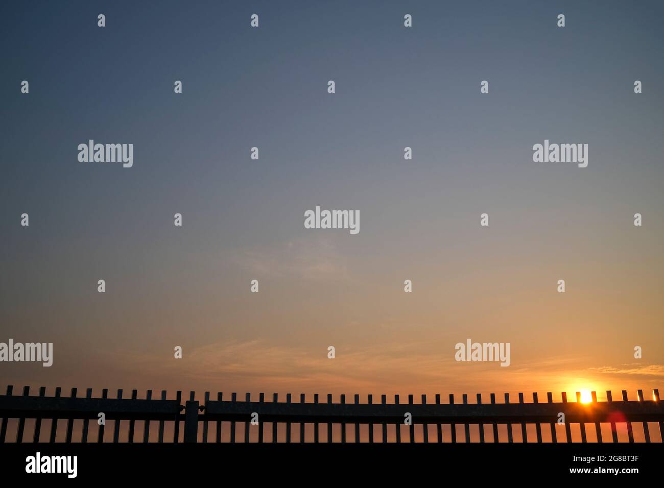 Sunrise over metallic fence Stock Photo
