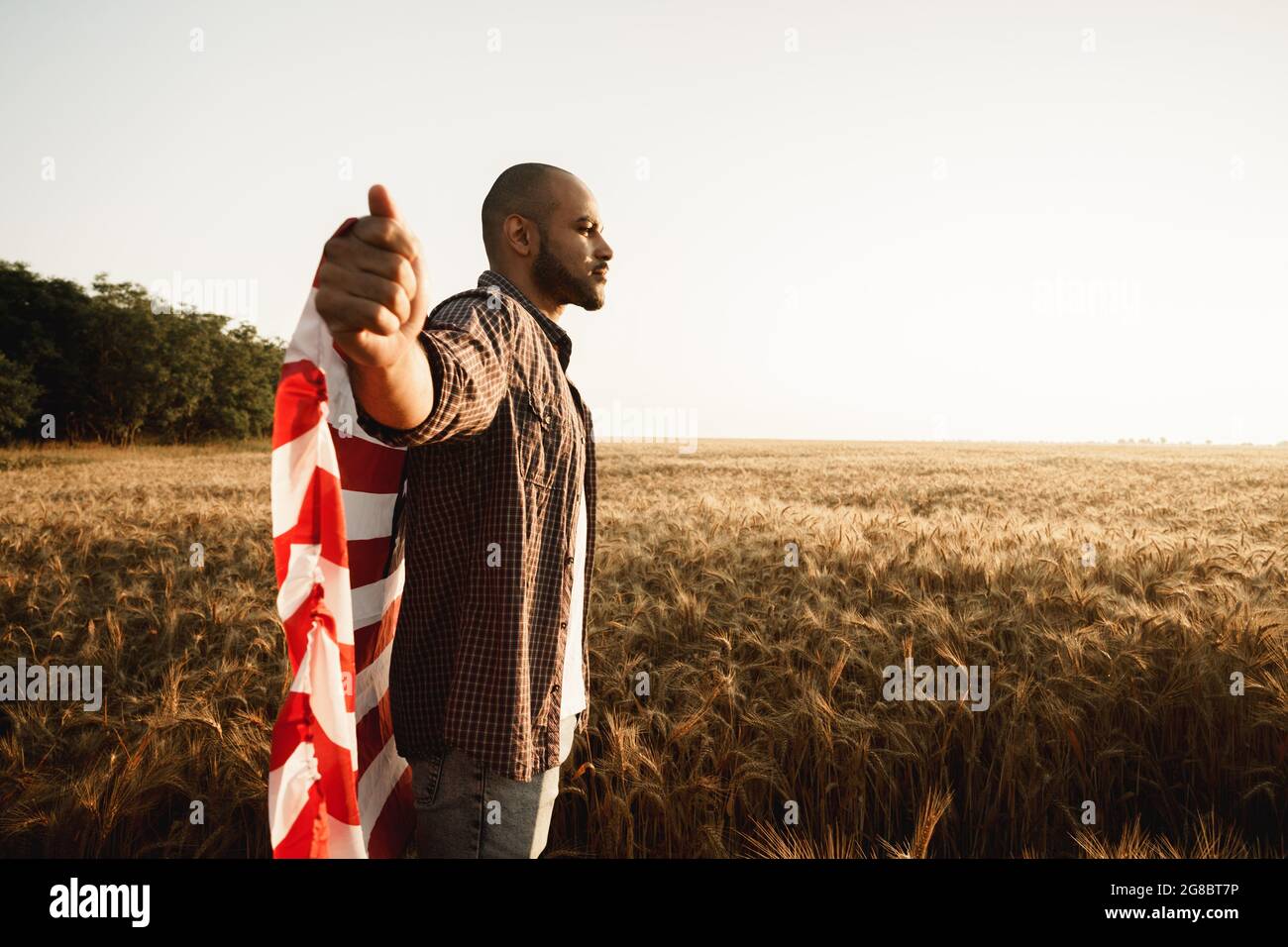 African american young man holding USA national flag through wheat ...