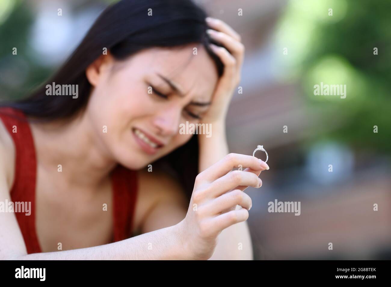 Sad asian woman complaining holding engagement ring in the street Stock Photo