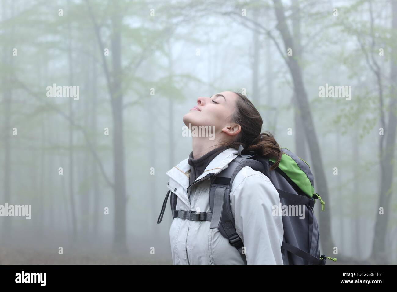 Side view portrait of a trekker breathing fresh air in nature a foggy day Stock Photo