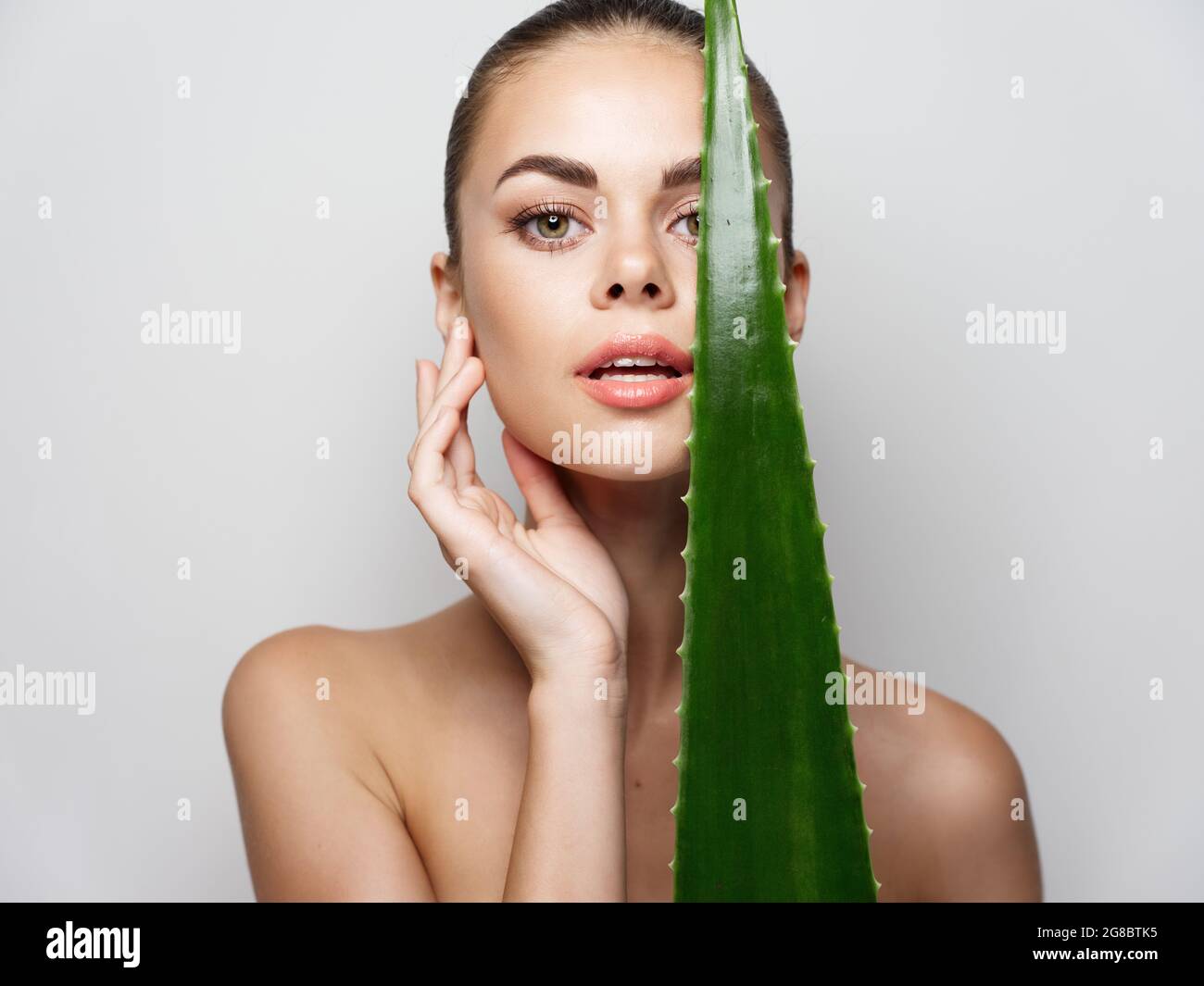 beautiful woman with green aloe leaf touching face with hand on gray background Stock Photo Alamy