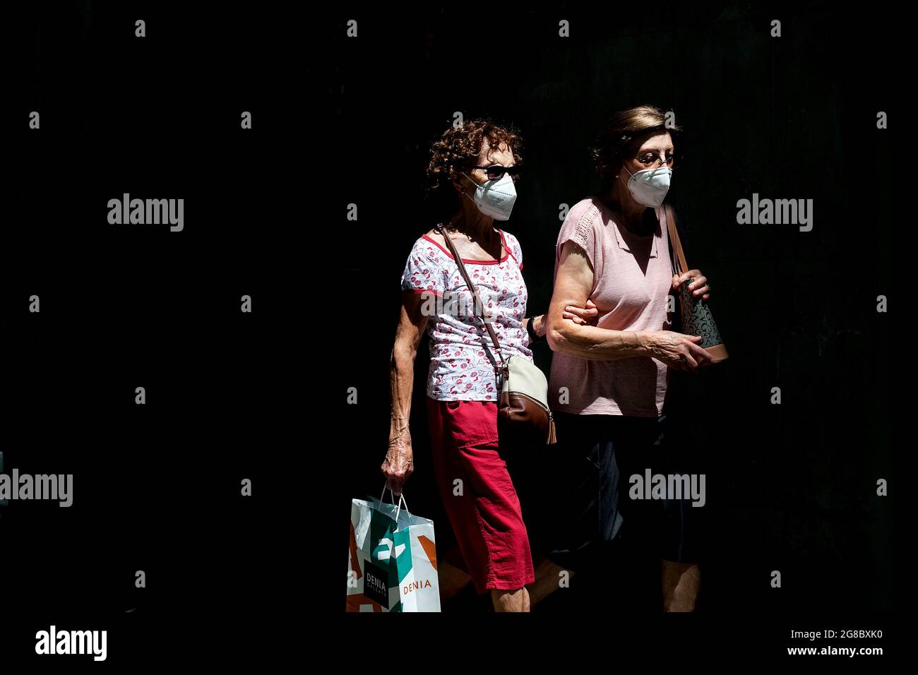Two masked women walking in the street, Barcelona, Spain. Stock Photo