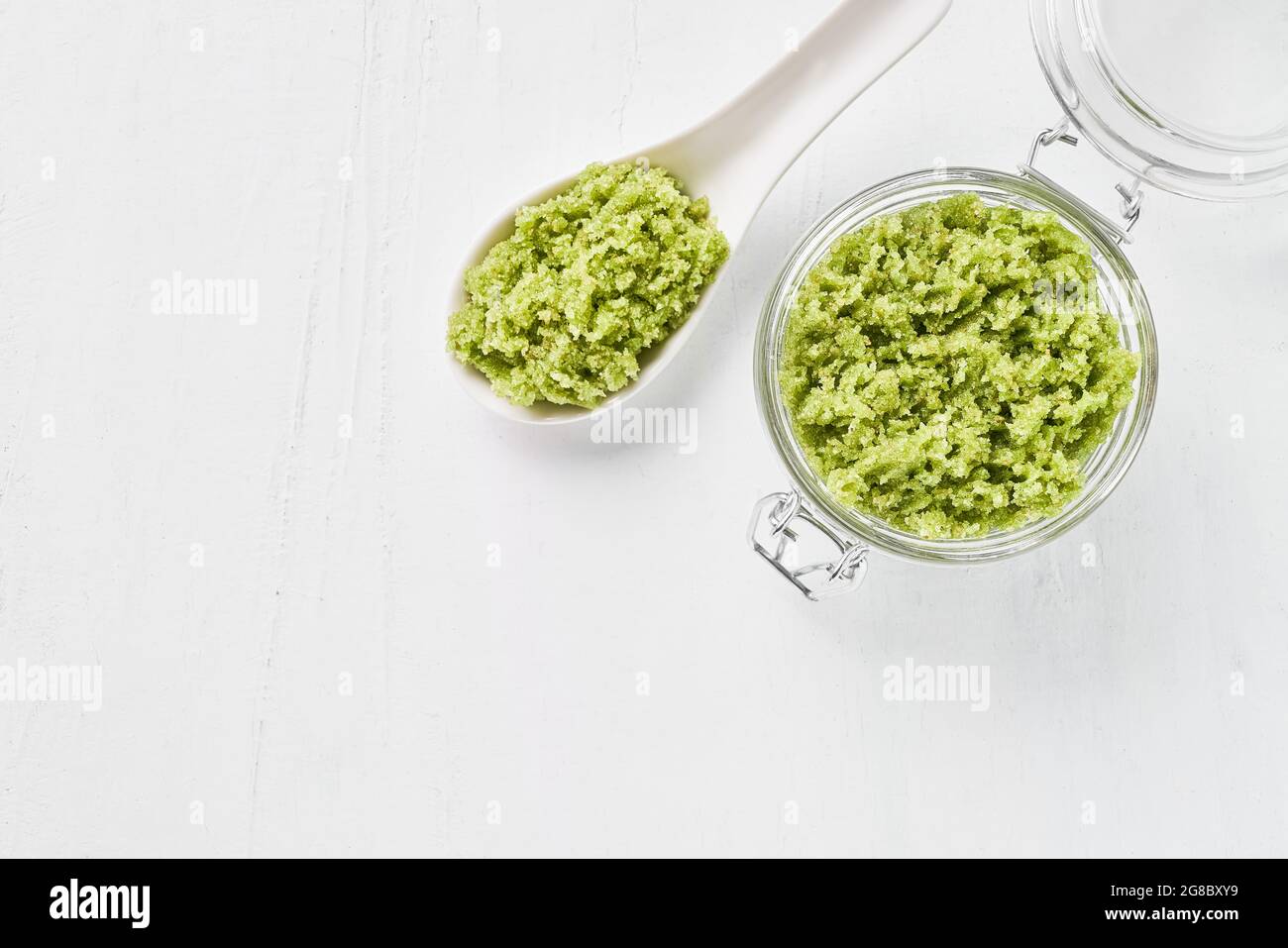 Homemade green body scrub in a glass jar on a white background. Top view, copy space for text. SPA concept. Selective focus Stock Photo