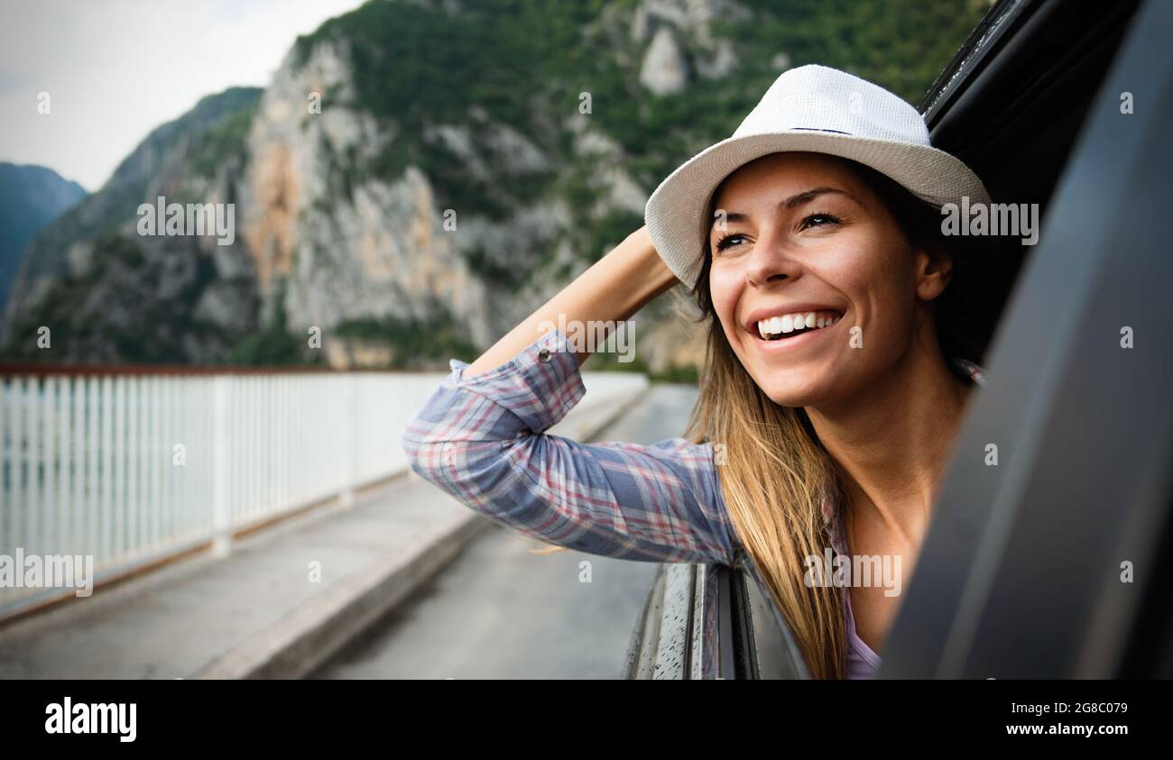 Woman in car road trip waving out the window smiling Stock Photo