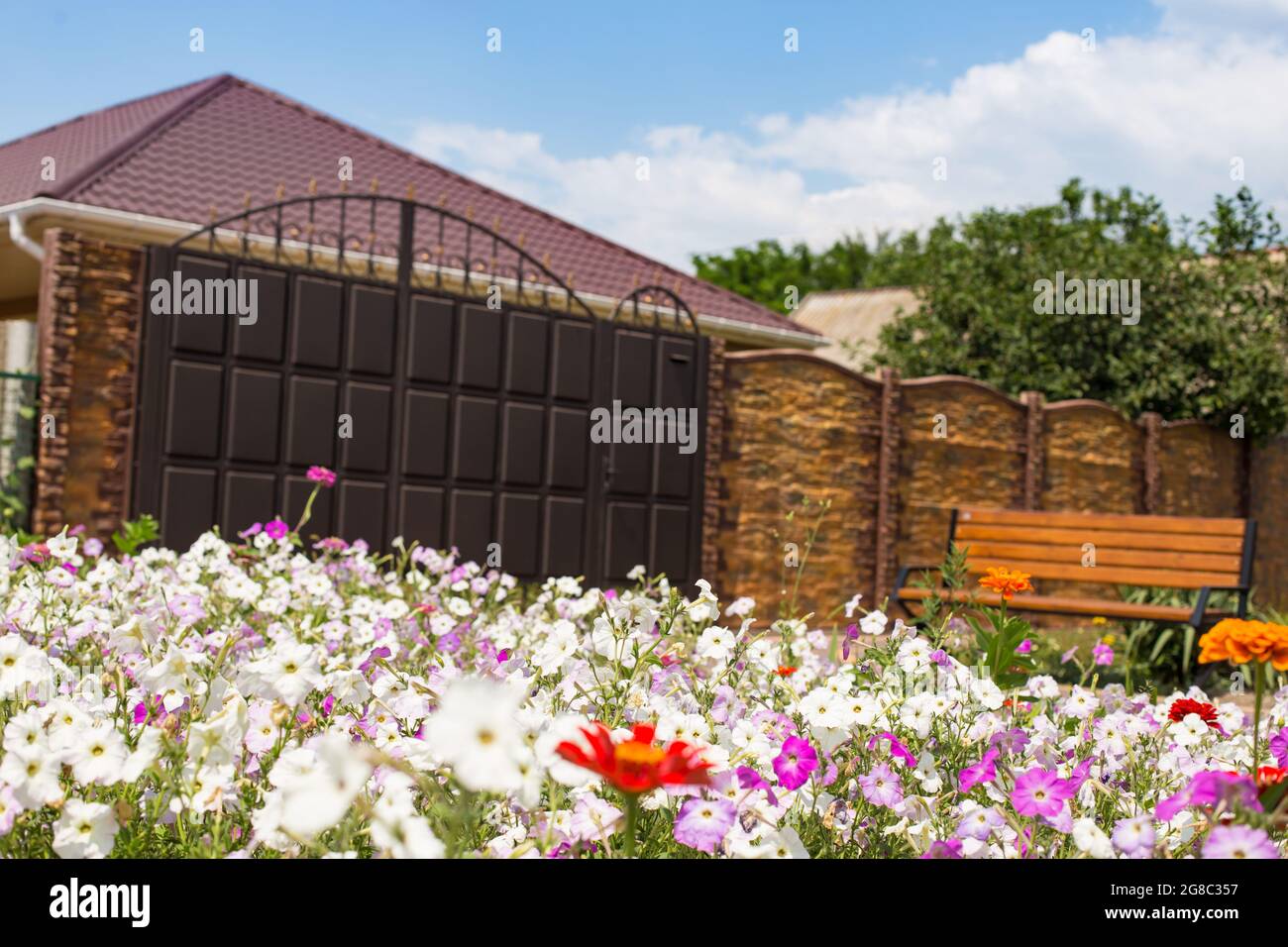 Garden with petunia flowers on a front of new big house. Stock Photo