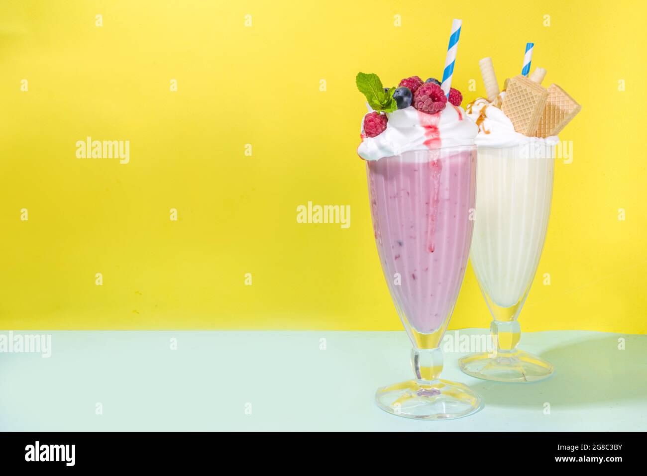 Summer refreshing drinks, milkshakes, crazy shakes with ice cream, berries, vanilla, chocolate. On a bright blue yellow background Stock Photo