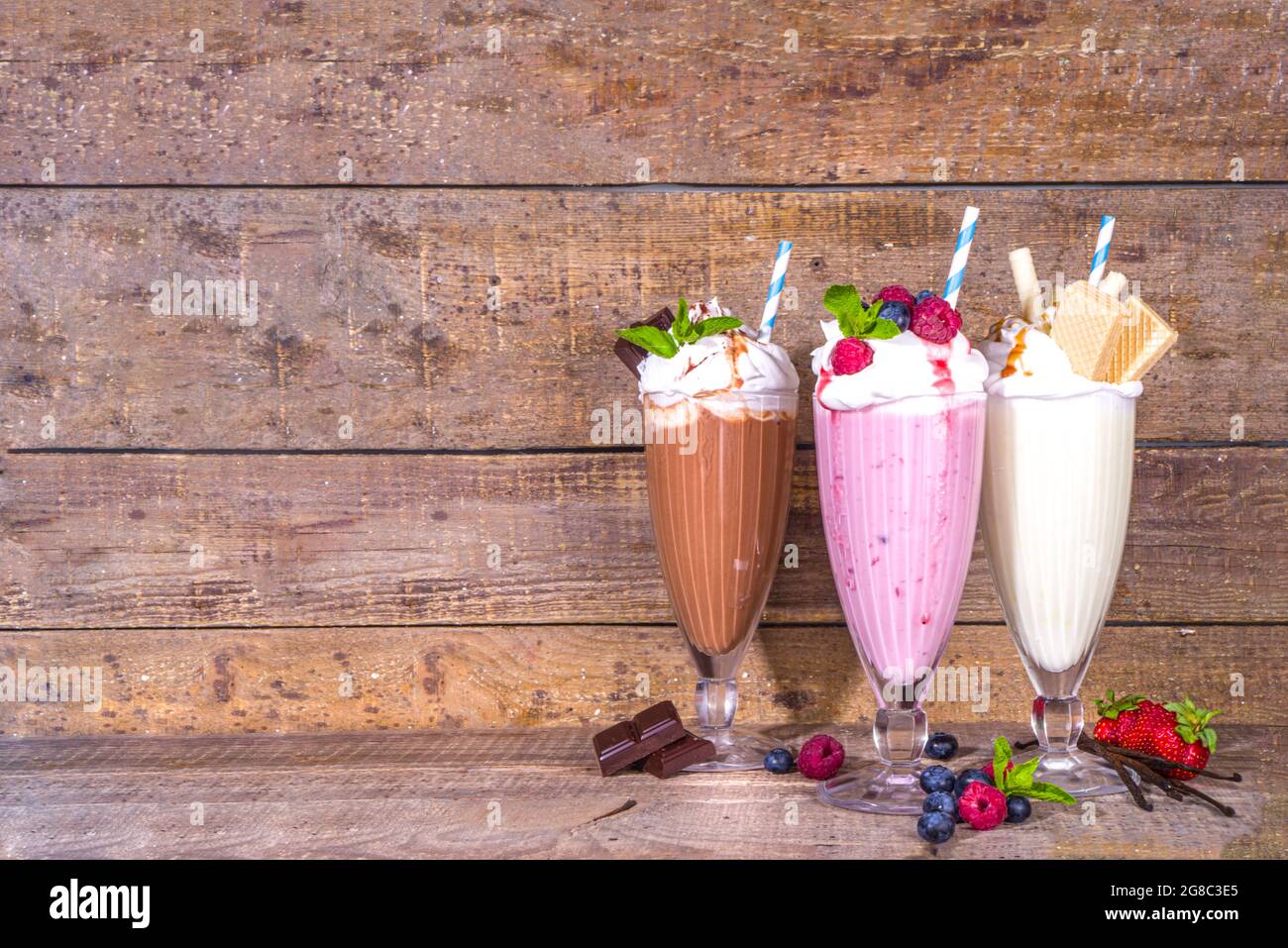Summer refreshing drinks, milkshakes, crazy shakes with ice cream, berries, vanilla, chocolate. On classic wooden background Stock Photo