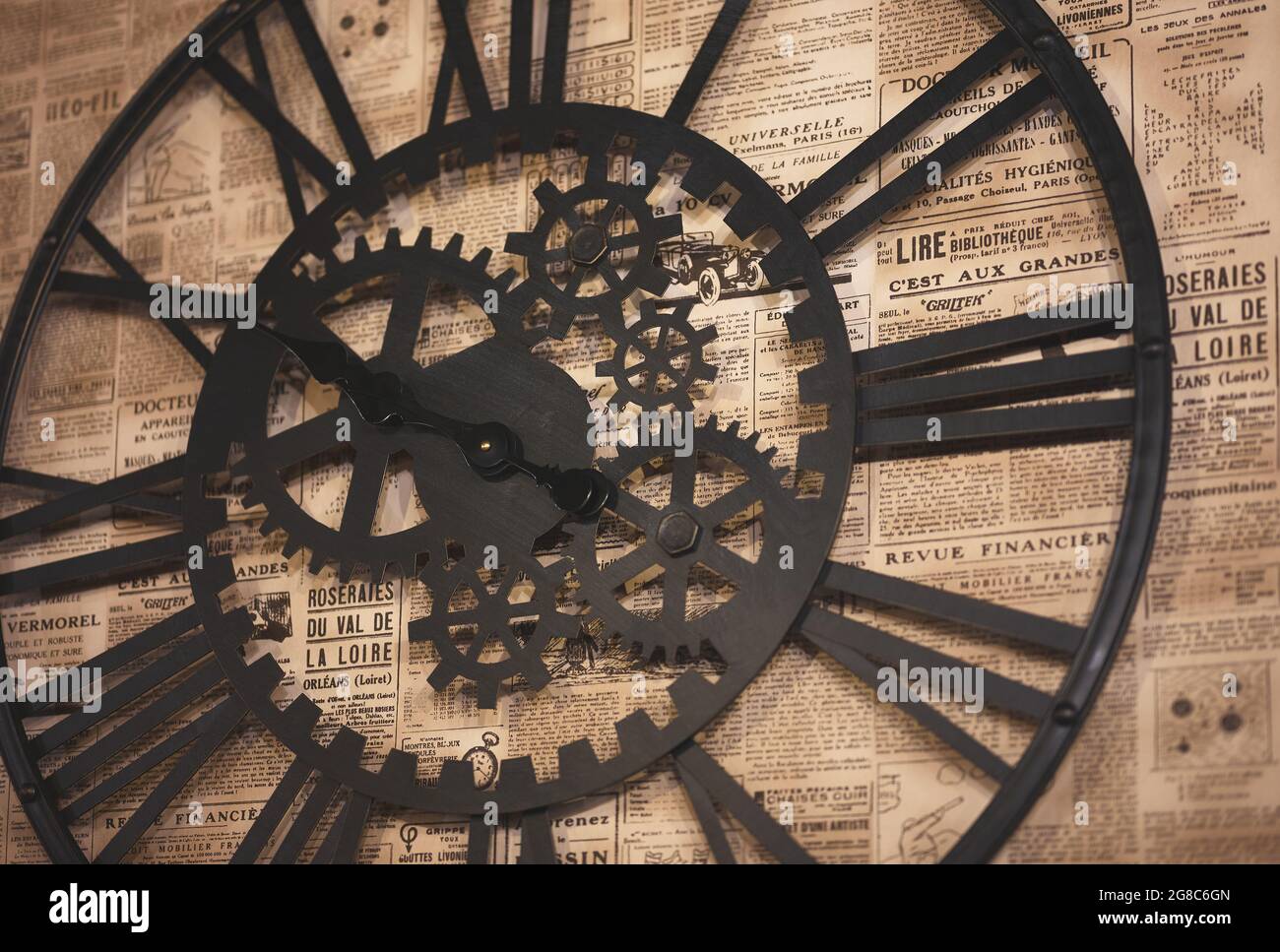 detail of a gearshaped wall clock on wallpaper with old newspaper