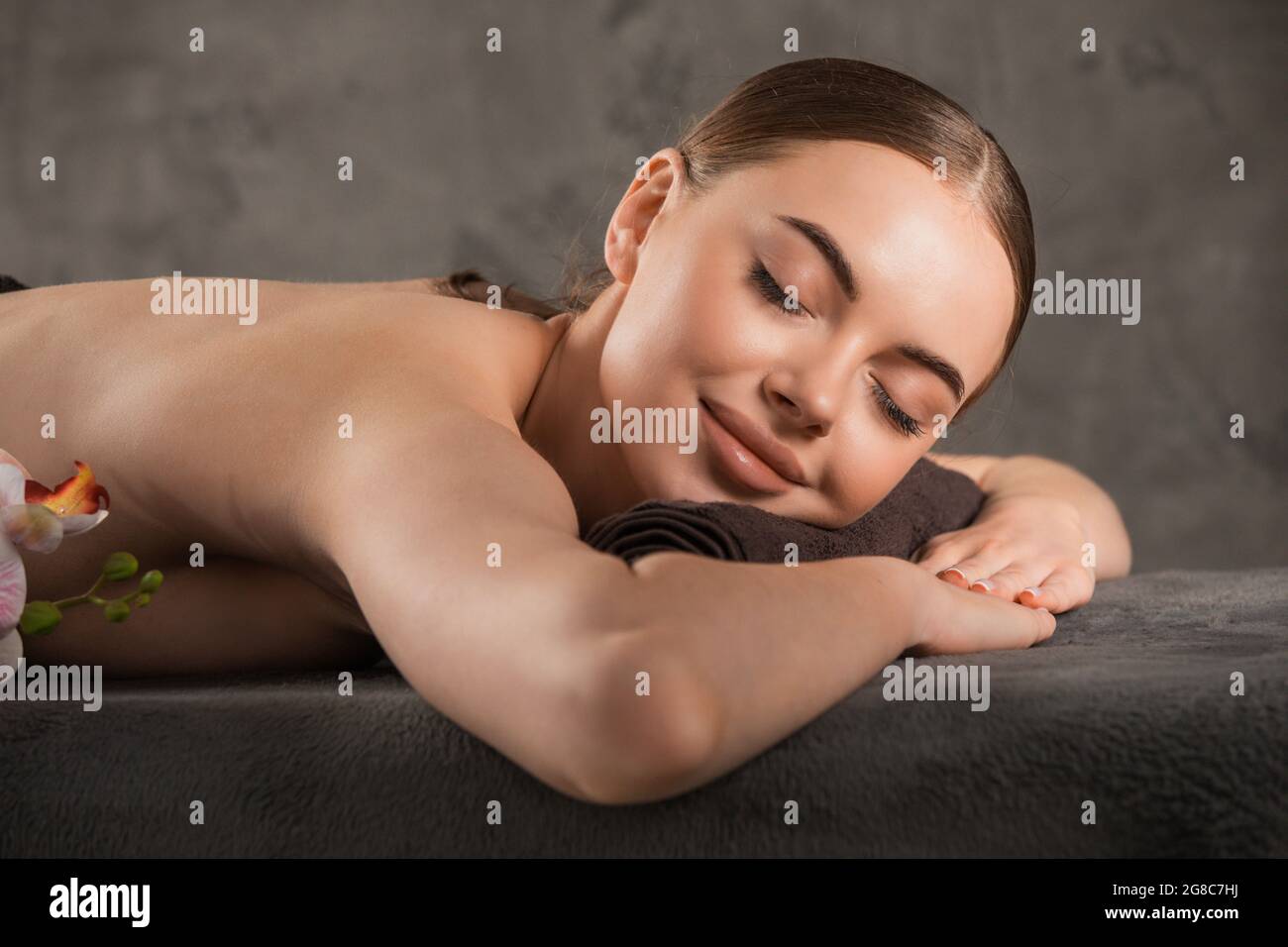 Close up of a smiling woman relaxing on a lounger with eyes closed in a ...