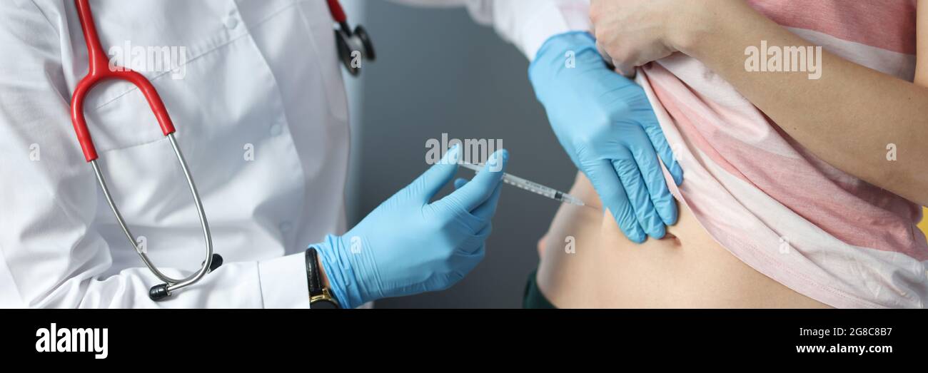 Doctor making injection of insulin into abdomen of female patient Stock