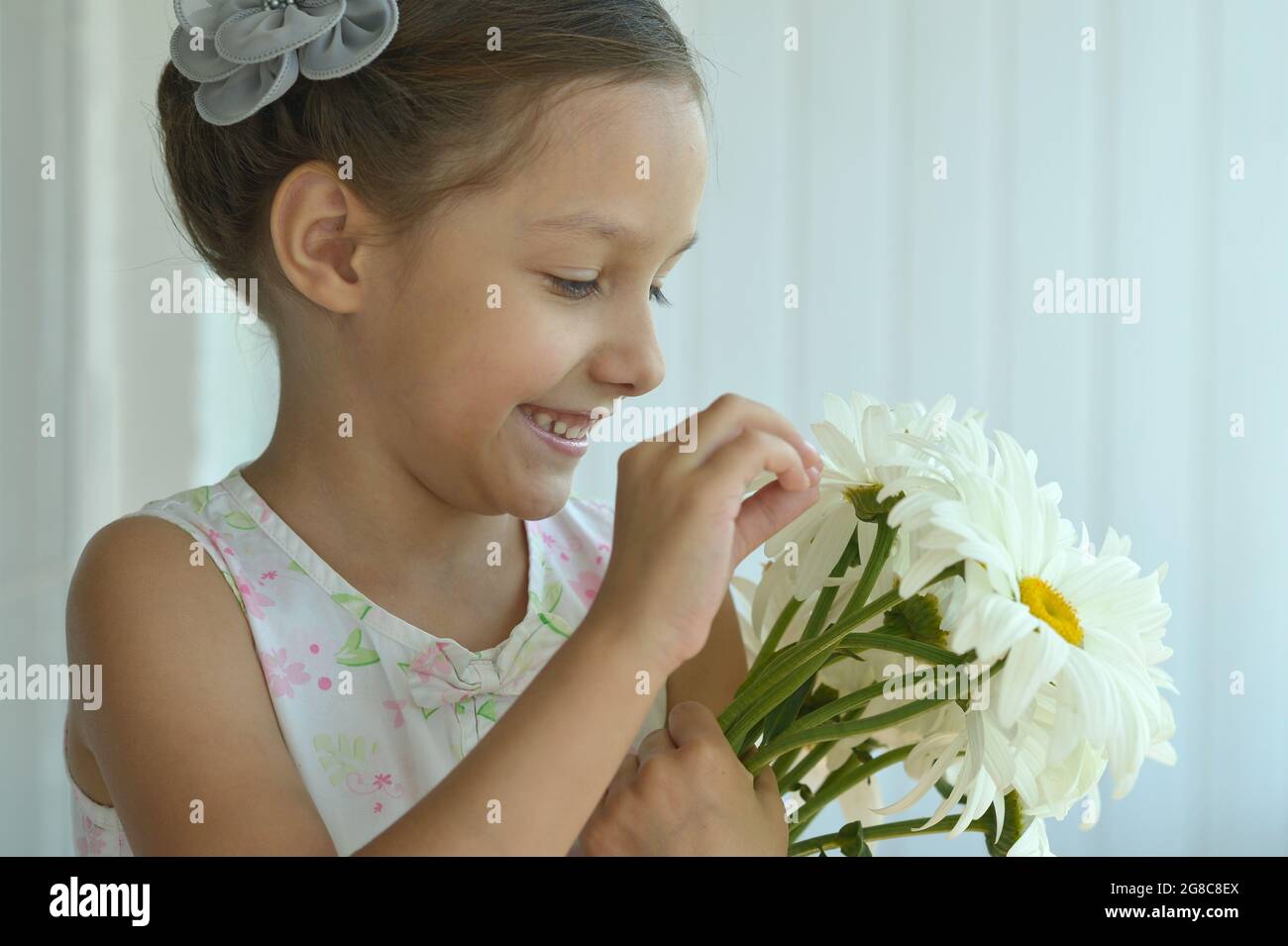 Cute little girl at home with chamomiles Stock Photo - Alamy