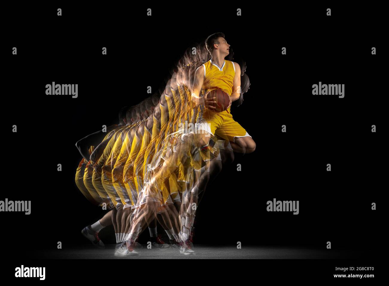 Power and speed. One young basketball player training with ball isolated on dark background with