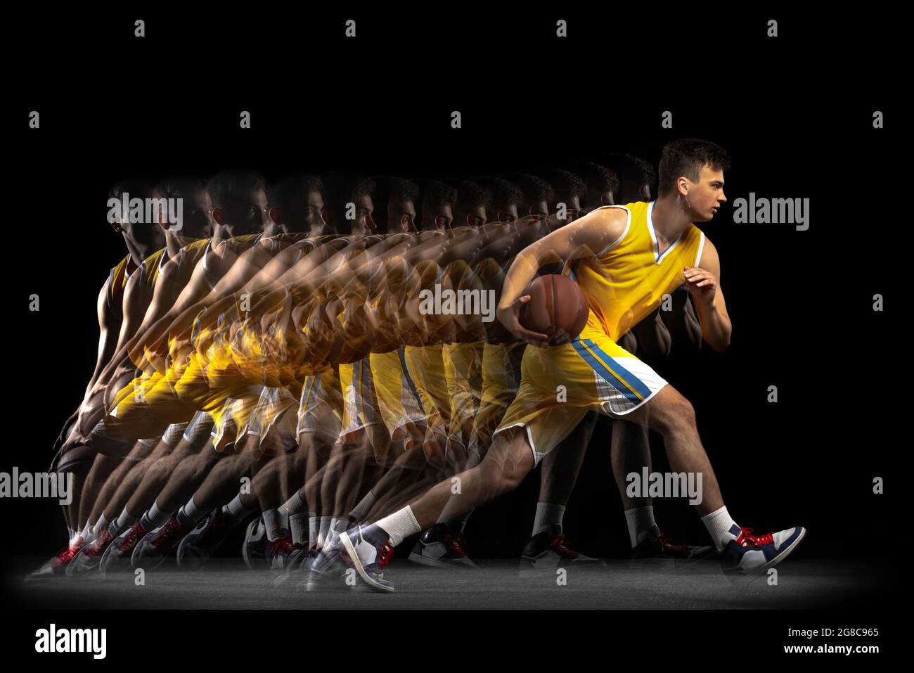 Power and speed. One young basketball player training with ball isolated on dark background with