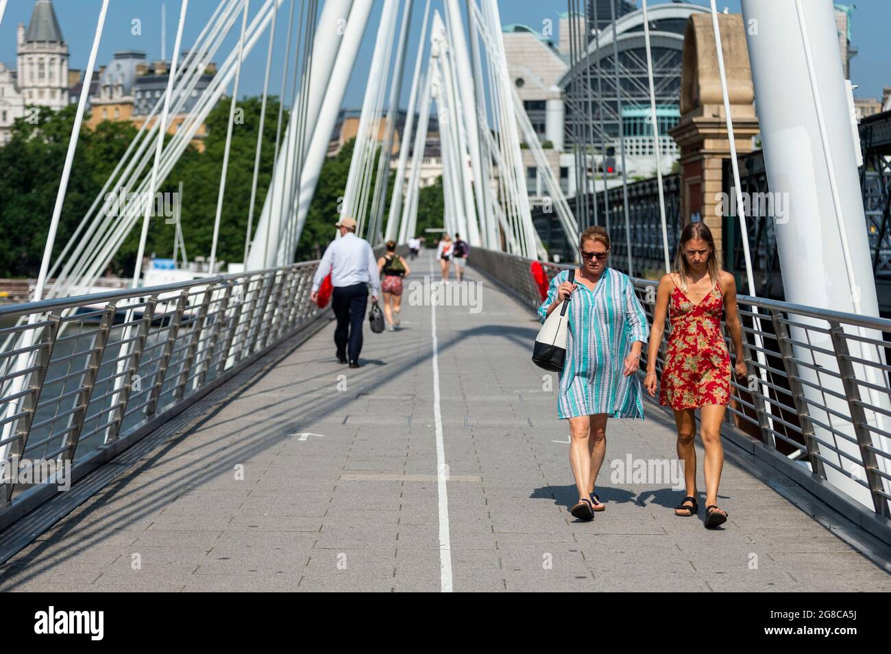 London, UK.  19 July 2021. People cross the Jubilee Bridge, adhering to social distancing lane markings on what has been dubbed “Freedom Day”, when the UK government has eased remaining coronavirus lockdown restrictions.  This comes against a backdrop of a rising number of daily positive cases, large numbers being required to self-isolate after being notified by the NHS app on their smartphones, including Boris Johnson, Prime Minister, Rishi Sunak, Chancellor, and Sajiv Javid, Health Secretary.  Credit: Stephen Chung / Alamy Live News Stock Photo