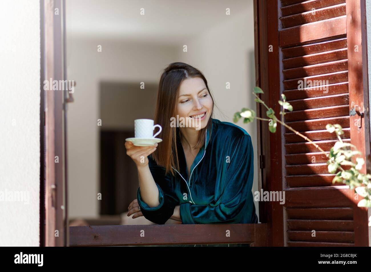 https://c8.alamy.com/comp/2G8CBJK/woman-in-pajamas-drinks-morning-coffee-near-window-with-shutters-beginning-of-a-new-day-hot-drink-after-breakfast-happy-morning-in-italy-enjoy-mom-2G8CBJK.jpg