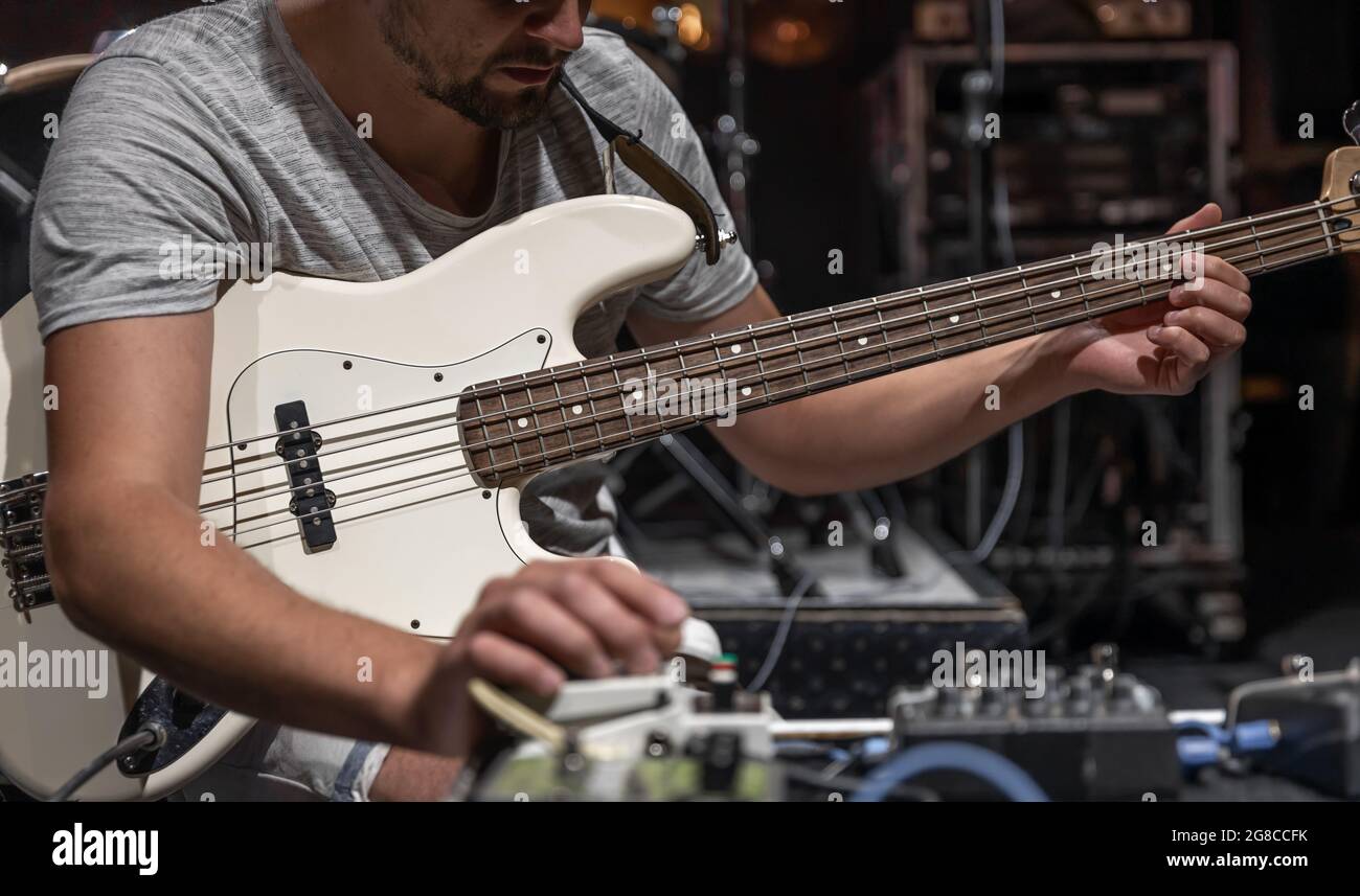 A male guitarist setting up guitar audio processing effects on stage