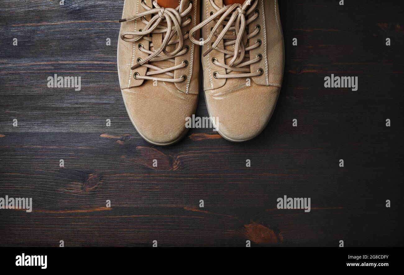 Sand-colored boots on brown wooden background. Flat lay. Stock Photo