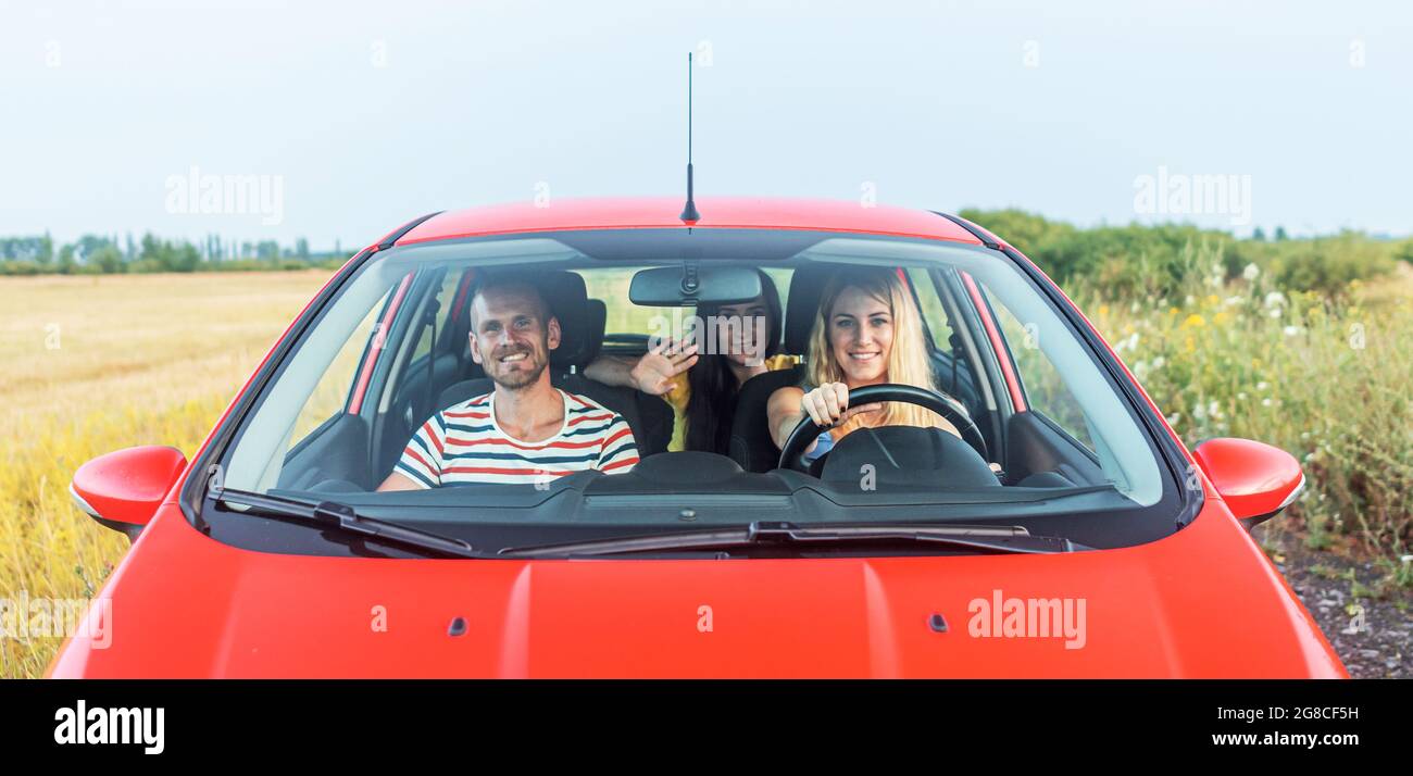 Friends in a red car. Travel freedom concept. Stock Photo