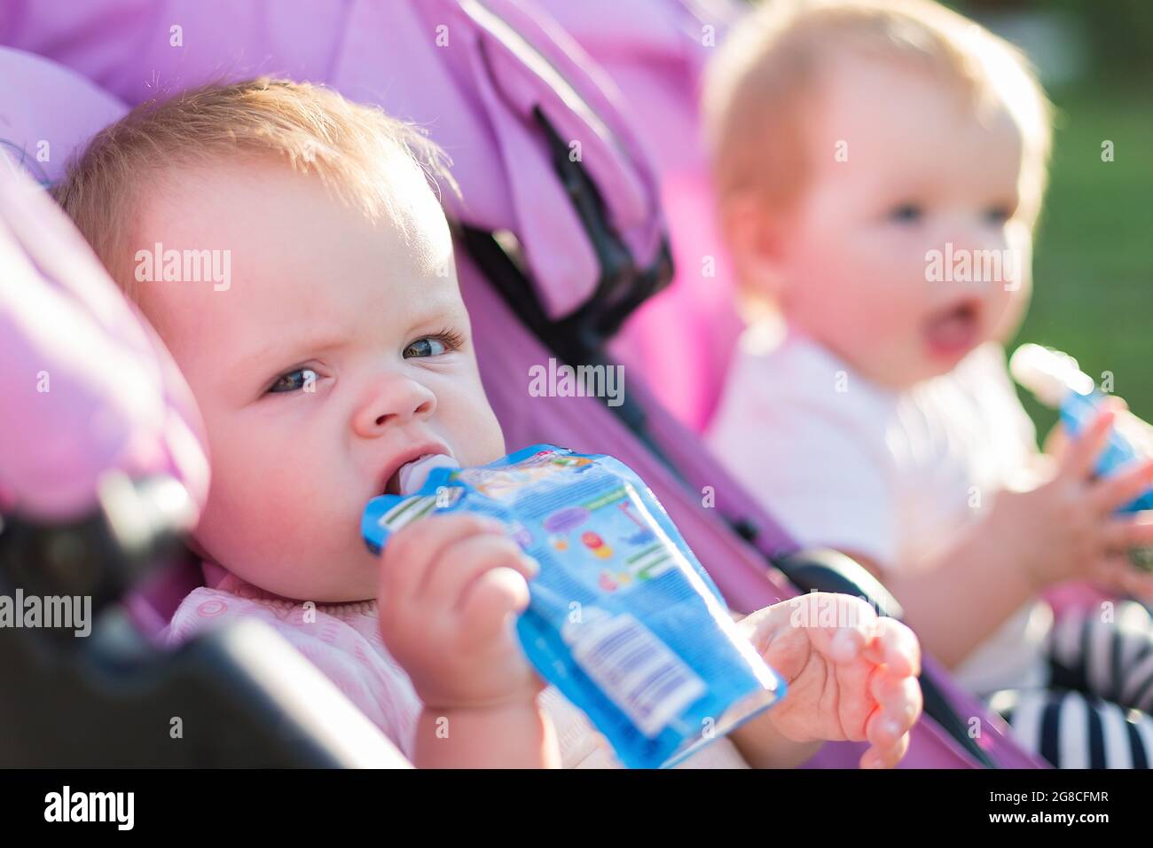 Portrait of hungry twin girls on the street with mashed potatoes in their hands. Stock Photo