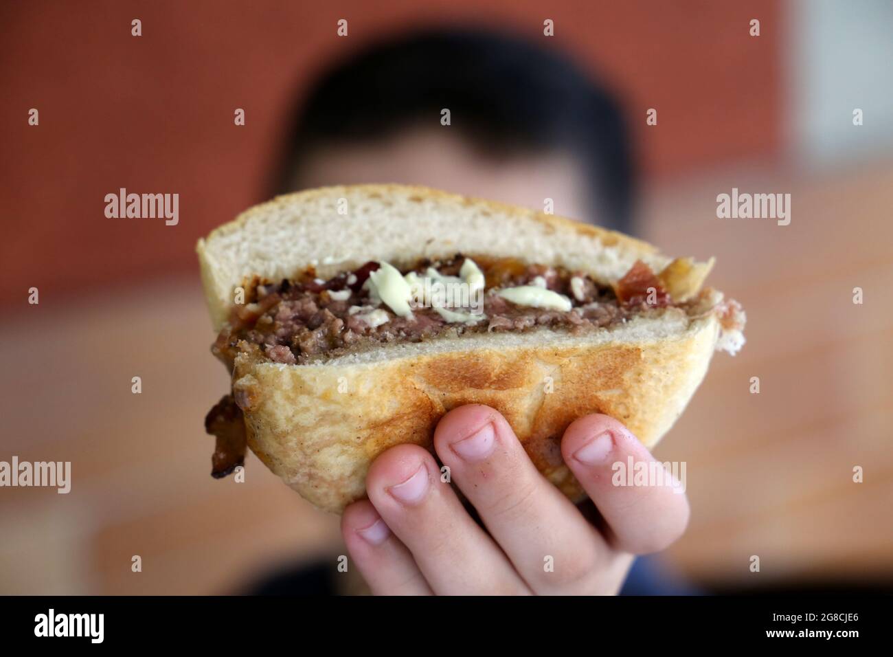 child's hand holding a burger in front of the camera. Stock Photo
