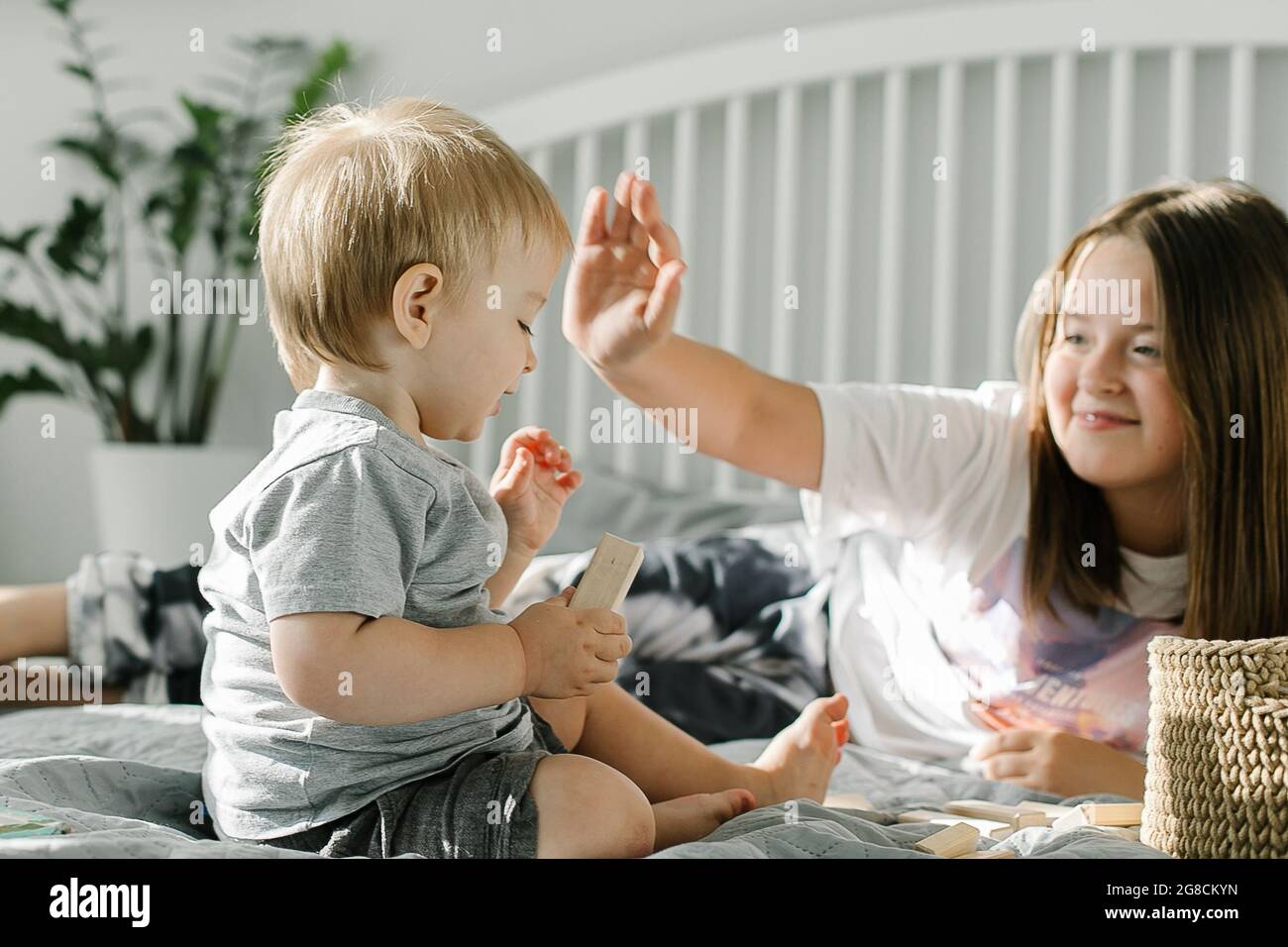 Younger brother and older sister playing with wooden blocks at home