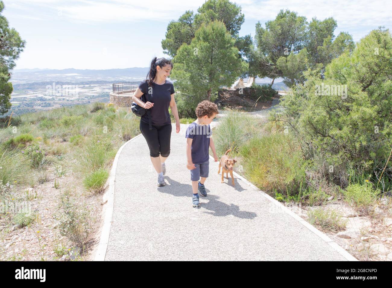mom with her son and puppy walking with joy and smiles on a sunny day in a mountain park Stock Photo