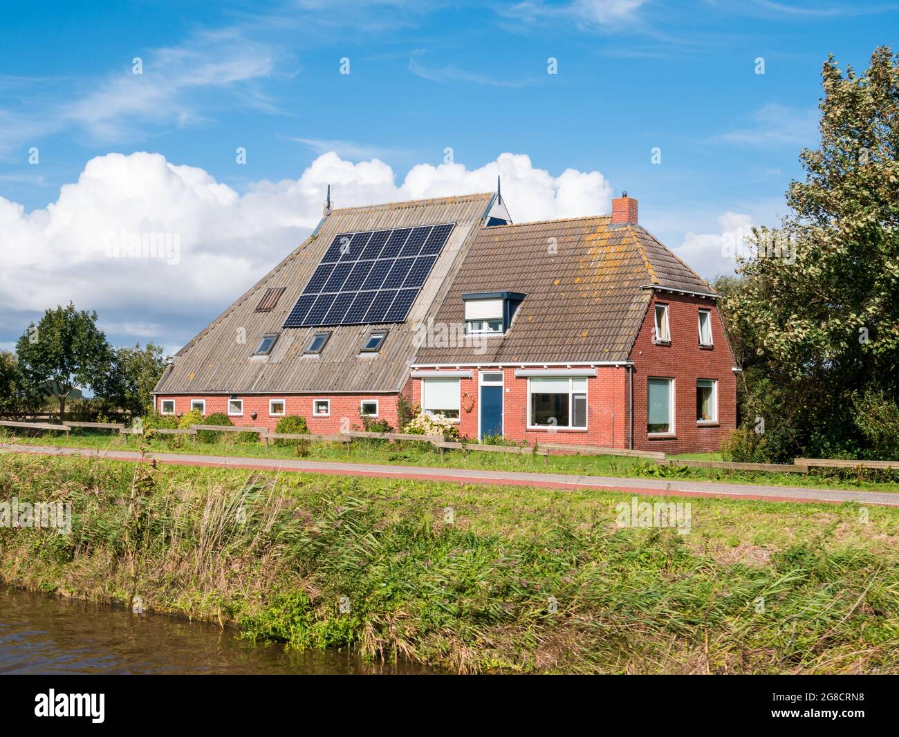 Farmhouse with 18 solar panels on roof by Dokkumer Ee canal in Friesland, Netherlands Stock Photo