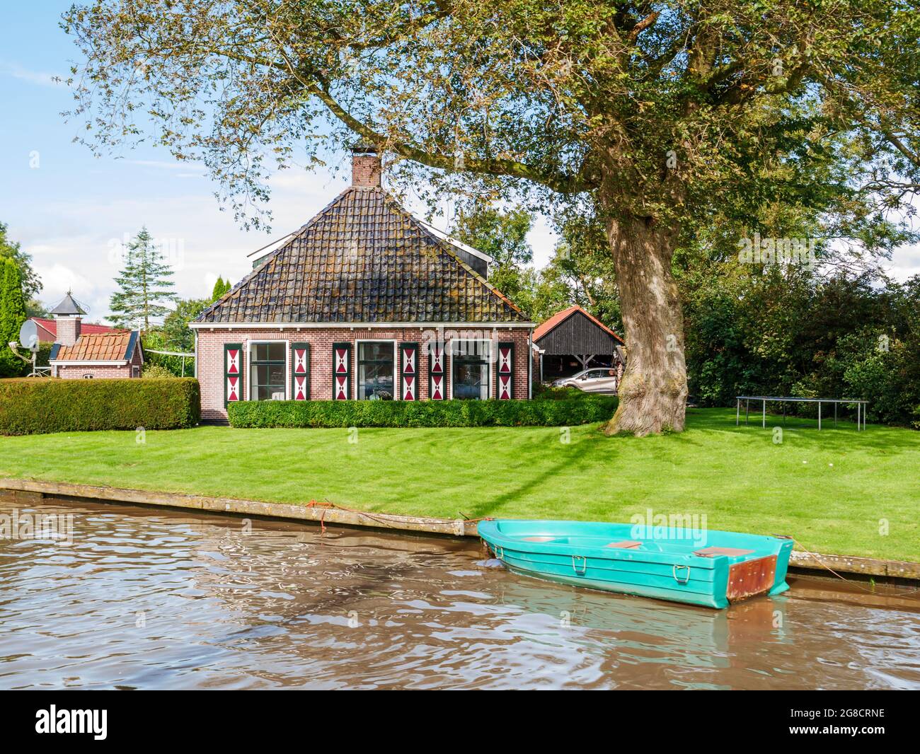 Traditional farmhouse with wooden shutters by Dokkumer Ee canal in old town of Birdaard, Friesland, Netherlands Stock Photo