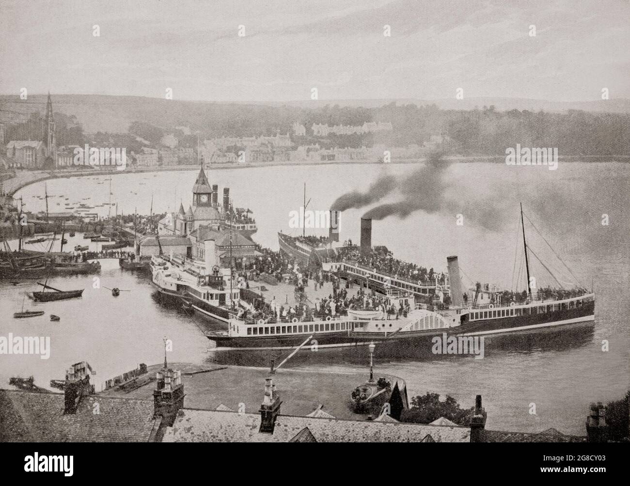 A late 19th century view of the harbour in Rothesay, the principal town on the Isle of Bute, lying on the coast of the Firth of Clyde in the council area of Argyll and Bute, Scotland. During the Victorian era, Rothesay became a popular tourist destination. In particular, it was hugely popular with Glaswegians going 'doon the watter' (literally “down the water” – a reference to the waters of the Firth of Clyde). Its wooden pier was busy with steamer traffic. It was home to one of Scotland's many hydropathic establishments, which were in vogue at the time. Stock Photo