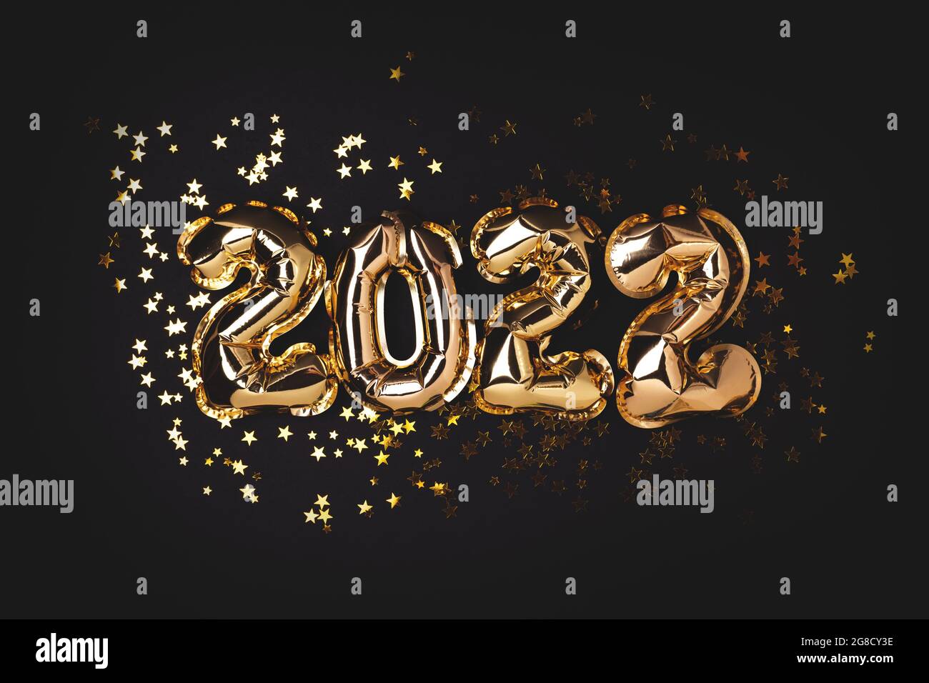 2022 gold balloons and stars confetti on a black background. Festive concept. Stock Photo