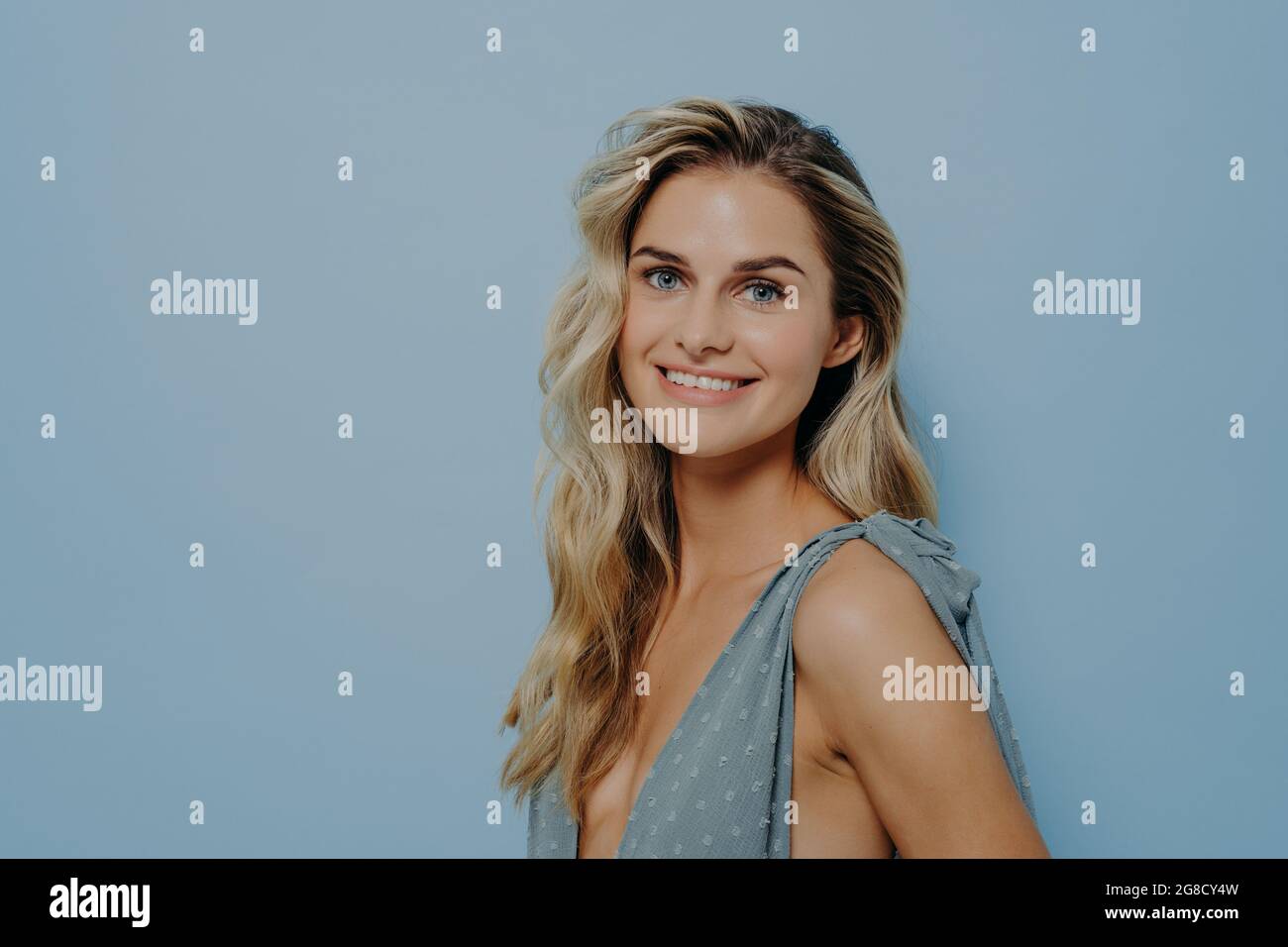 Cheerful smiling blonde girl in blue dress posing in studio Stock Photo ...