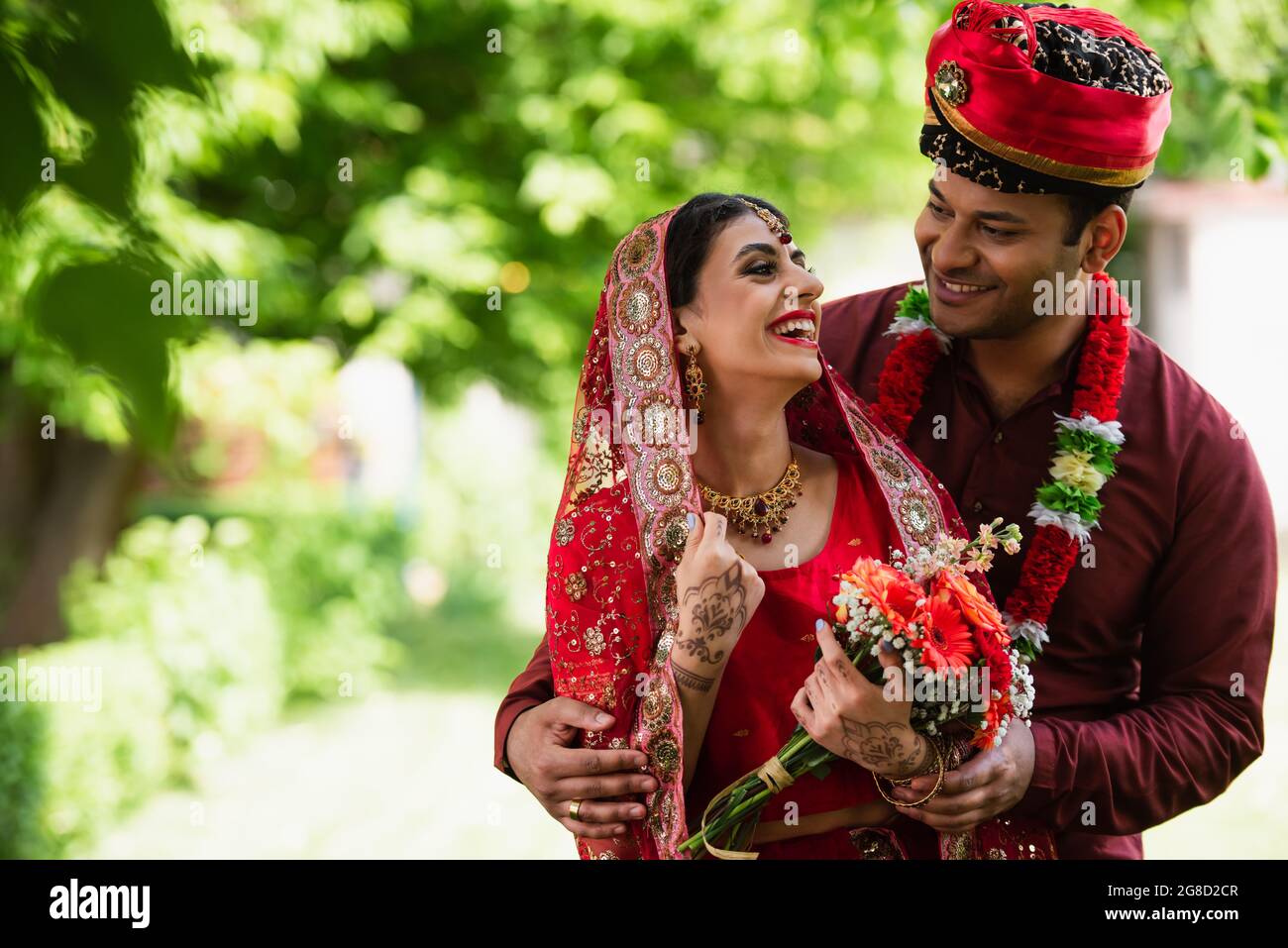 happy indian married couple in traditional wedding clothes looking at each other outside Stock Photo