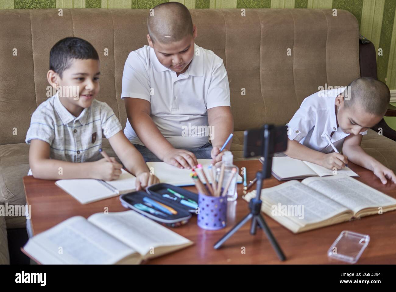 Remote Class Pictures Male pupils listening to an online class while taking notes at home ...